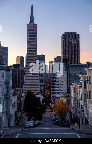 Le crépuscule s'installe sur San Francisco, vu dans une rue escarpée vers la Transamerica Pyramid et le quartier financier. Banque D'Images