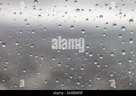 Gouttelettes de pluie sur une fenêtre en verre avec paysage urbain flou en arrière-plan Banque D'Images