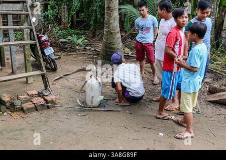 An Giang, Vietnam. 29 mars 2025. Dans la fraîcheur de l'aube, avant la chaleur de la journée, un pêcheur vietnamien prépare l'équipement pour la pêche électrique dans les rivières et ruisseaux du delta du Mékong, en utilisant une batterie de voiture dans un tambour en plastique et un onduleur haute tension fait maison fournissant un courant pulsé de l'anode à la cathode à travers l'eau. Bien que courante, cette pratique est dangereuse pour les humains et l'environnement. La pêche électrique récréative est considérée comme braconnant et interdite dans les zones d'eau douce, ainsi que toutes les méthodes destructrices d'extraction des ressources aquatiques, sauf dans les étangs domestiques. Crédit : Kevin Izorce/Alamy Live News Banque D'Images
