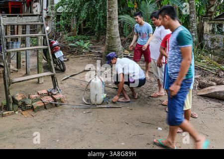 An Giang, Vietnam. 29 mars 2025. Dans la fraîcheur de l'aube, avant la chaleur de la journée, un pêcheur vietnamien prépare l'équipement pour la pêche électrique dans les rivières et ruisseaux du delta du Mékong, en utilisant une batterie de voiture dans un tambour en plastique et un onduleur haute tension fait maison fournissant un courant pulsé de l'anode à la cathode à travers l'eau. Bien que courante, cette pratique est dangereuse pour les humains et l'environnement. La pêche électrique récréative est considérée comme braconnant et interdite dans les zones d'eau douce, ainsi que toutes les méthodes destructrices d'extraction des ressources aquatiques, sauf dans les étangs domestiques. Crédit : Kevin Izorce/Alamy Live News Banque D'Images