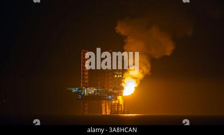 Doha, Qatar - 14 janvier 2024, vue panoramique de la plate-forme pétrolière, qui brûle l'excès de gaz naturel, pendant la production de pétrole, dans le golfe Persique, la nuit, Doha, Banque D'Images