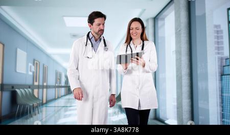 Médecins parlant à l'hôpital, homme d'affaires consultant avec le personnel de santé, chirurgien analysant. Banque D'Images