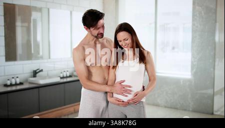 Couple joyeux embrassant dans une salle de bain lumineuse ensemble. Banque D'Images