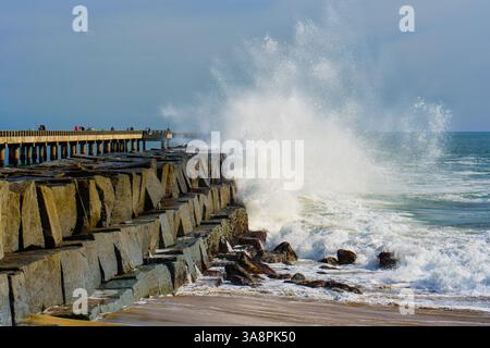 Scène dynamique de puissantes vagues océaniques s'écrasant contre le rivage rocheux à Cabrillo Beach Pier, mettant en valeur la puissance naturelle de la mer contre un vibra Banque D'Images