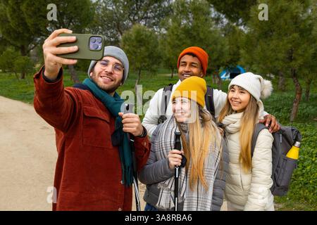 Groupe de jeunes randonneurs prenant un selfie avec smartphone tout en profitant d'une journée de trekking dans les bois Banque D'Images
