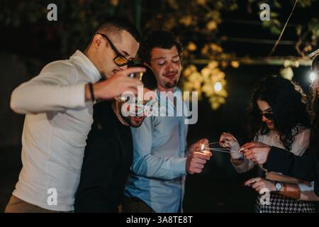 Groupe d'amis célébrant avec des pétillants en plein air lors d'une soirée festive Banque D'Images
