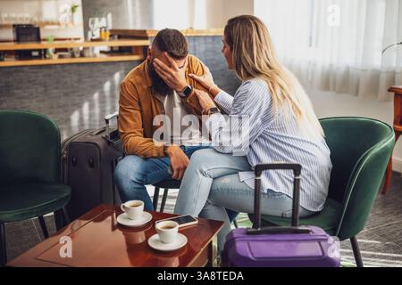 Couple adulte se disputant dans le hall de l'hôtel. Ils attendent leur chambre. Banque D'Images