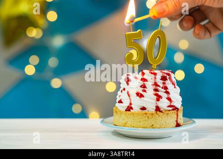 50e anniversaire. Femme allumant des bougies en forme de numéro sur cupcake à la table en bois blanc contre les lumières floues, gros plan et espace pour le texte. Effet bokeh Banque D'Images