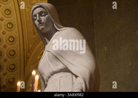 Angle vers le haut gros plan d'une statue en marbre blanc de la Sainte Vierge mère Marie (Maria, Madonna) priant dans une belle église catholique. Banque D'Images