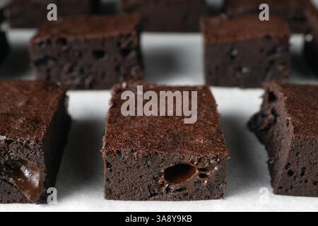 Gros plan d'un brownie au chocolat. Les brownies sont disposés en rangées sur une surface blanche Banque D'Images