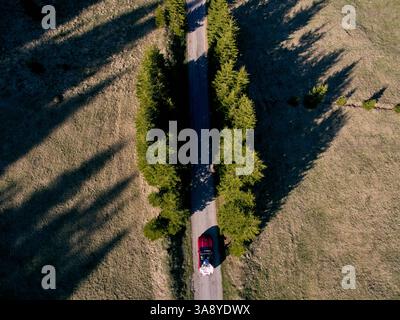 Monténégro, Zabljak - 09 mai 2024 : mariés et mariés roulent dans un cabriolet le long de l'autoroute parmi les arbres. Vue de dessus Banque D'Images