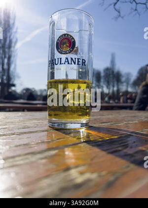Verre à bière Paulaner à moitié rempli sur une table de jardin de bière altérée, derrière elle visiteurs de jardin de bière, Kleinhesseloher See, Munich, Bavière, Allemagne, Europ Banque D'Images
