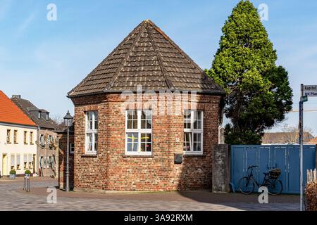 Un petit bâtiment en briques avec un toit vert à Xanten Allemagne. Le toit est incliné. Il y a un vélo appuyé contre le bâtiment Banque D'Images
