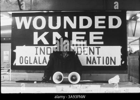 30 octobre 2017 - DENNIS BANKS, co-fondateur du mouvement des Indiens d'Amérique et leader de l'occupation Wounded Knee de 1973, est décédé, a annoncé lundi sa famille. Il avait 80 ans. Banks est l'un des nombreux militants qui fondent le mouvement des Indiens d'Amérique à Minneapolis en 1968, et il est l'un des chefs de file de la prise de contrôle armée de Wounded Knee sur la réserve de Pine Ridge dans le Dakota du Sud en 1973, pour protester contre les gouvernements tribaux et américains. PHOTO : 1985 - Dakota du Sud États-Unis - DENNIS BANKS sous un panneau Wounded Knee. (Crédit image © Kevin McKiernan/ZUMAPRESS.com) Banque D'Images