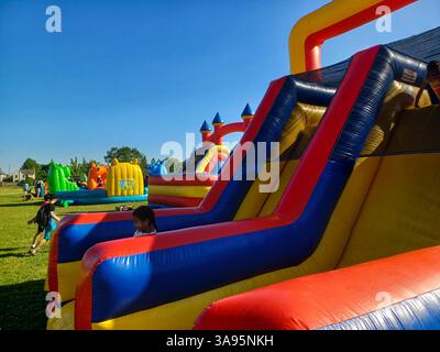 Toronto, ON, Canada – 31 mai 2024 : les familles se rassemblent autour de grands toboggans gonflables et de parcours d’obstacles lors d’un événement pour enfants par un après-midi ensoleillé. Banque D'Images