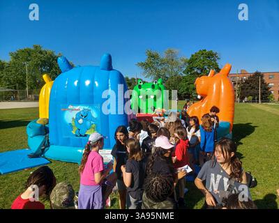 Toronto, ON, Canada – 31 mai 2024 : les familles se rassemblent autour de grands toboggans gonflables et de parcours d’obstacles lors d’un événement pour enfants par un après-midi ensoleillé. Banque D'Images
