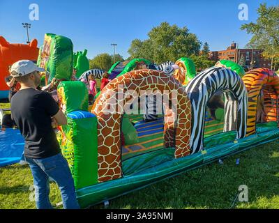 Toronto, ON, Canada – 31 mai 2024 : les familles se rassemblent autour de grands toboggans gonflables et de parcours d’obstacles lors d’un événement pour enfants par un après-midi ensoleillé. Banque D'Images