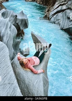 Femme touriste voyageant en solo en Norvège couchant sur une falaise rocheuse au-dessus des vacances d'été fluviales en plein air, fille voyageuse se relaxant trouver l'équilibre Banque D'Images