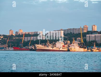 Navires amarrés dans le port de Vladivostok avec l'horizon de la ville en arrière-plan pendant une soirée claire. Banque D'Images