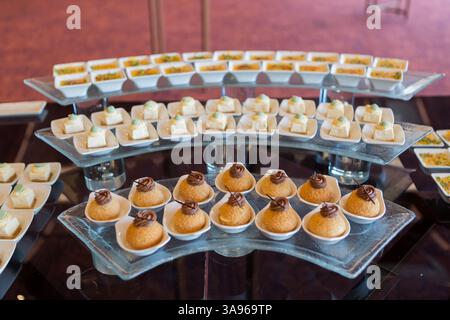 Une table élégante remplie de desserts et de pâtisseries, magnifiquement agencée pour un événement spécial, offrant une sélection alléchante de friandises sucrées. Banque D'Images