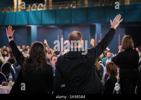 Groupe de personnes lève la main pendant un événement professionnel dans un cadre de conférence Banque D'Images