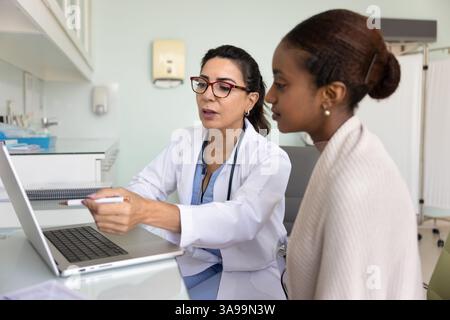 Médecin féminin mature montrant le résultat de l'examen à la femme patiente noire Banque D'Images