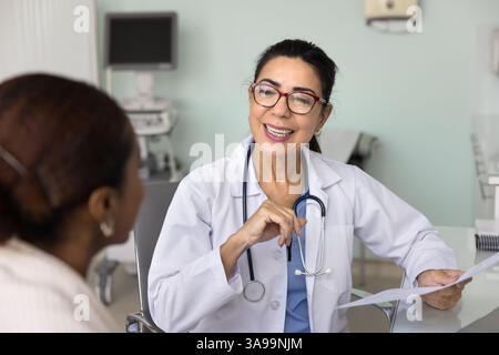 Médecin féminin expérimenté et joyeux donnant consultation à un jeune patient Banque D'Images