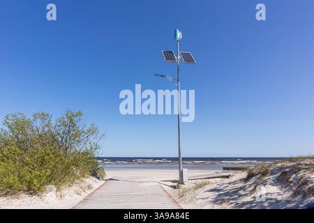 lampadaire avec panneaux solaires sur un chemin de plage surplombant la mer. Banque D'Images