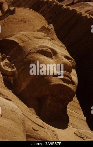 Graffiti piraté dans la joue de pierre de l'ancien Pharaon égyptien du nouvel Empire, Ramsès II, dévisage l'un des quatre colosses du puissant souverain flanquant l'entrée du Grand Temple qu'il a construit à Abu Simbel dans le désert de Nubie il y a environ 3 300 ans. Banque D'Images