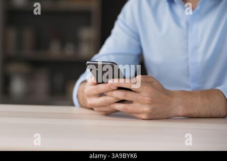 Homme abattu assis à son bureau tenant son téléphone dans les mains Banque D'Images