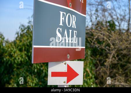 Pour la vente signe avec une flèche rouge, placé à l'extérieur pointant vers la propriété. Maison à vendre, à vendre conseil Banque D'Images