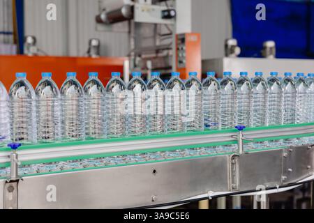 Ligne de production d'eau potable sur bande transporteuse. Bouteilles d'eau en plastique PET dans l'usine de boisson. Industrie des bouteilles PET. Banque D'Images