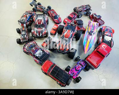 Diverses voitures Traxxas télécommandées et bateau disposés en forme de coeur sur plancher de béton. Suède. Banque D'Images