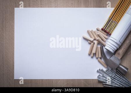 Plans roulés de mètre en bois clous de papier blanc clous de marteau de griffe goujons de travail du bois sur le concept de construction d'espace de copie de panneau de bois Banque D'Images