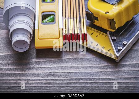 Mètre carré en bois mètre mètre ruban de mesure roulé plans et niveau de construction sur le concept de maintenance de panneau de bois vintage Banque D'Images