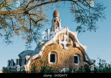 Maison Gaudi de conte de fées dans le parc Guell, encadrée par des branches d'arbres Banque D'Images