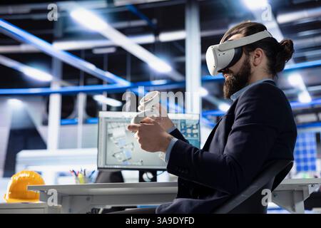 Technicien d'usine photovoltaïque utilisant l'équipement VR pour ajuster les paramètres du système, maximisant la production d'énergie. Homme utilisant la technologie de réalité virtuelle, optimisant l'approvisionnement en énergie dans l'usine de panneaux solaires Banque D'Images