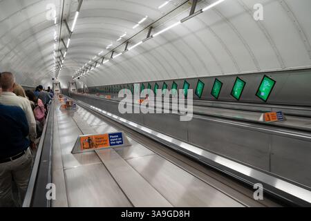 Londres, Angleterre, 11 juillet 2023, les navetteurs empruntent un long escalier roulant dans le métro londonien, entouré de lumières brillantes et de publicités numériques, mettant en vedette le Banque D'Images
