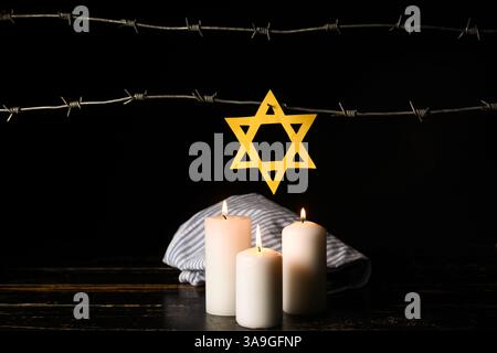 Uniforme de prisonnier, étoile de David, bougies allumées et barbelés sur fond sombre. Jour du souvenir de l'Holocauste Banque D'Images