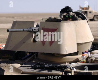 17 mars 2006 ; Samarra, IRAK ; Un soldat de l'armée américaine du 2e bataillon, 9e régiment de cavalerie dans une tourelle d'un M2A2 Bradley regarde à travers des jumelles pour l'activité ennemie du point de blocage 21 pendant l'opération Swarmer, Nord-est de Samarra. Des points de blocage ont été établis autour de la zone principale de l'objectif au cours de l'opération pour bloquer toute voie de fuite des insurgés. Près de 1 500 soldats américains et irakiens, 50 hélicoptères d’attaque et de transport, et 200 véhicules terrestres sont sortis lors de l’opération au nord-est d’ad Dawr et Samarra, à la recherche de caches d’armes et d’insurgés présumés. L'opération est le plus grand air Banque D'Images