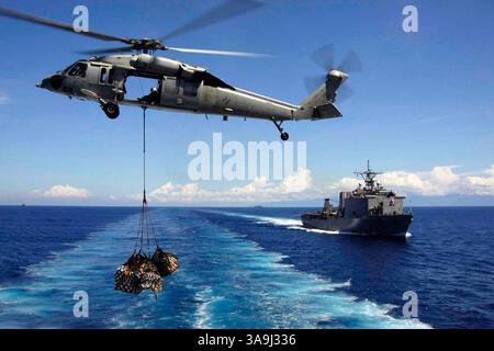 14 janvier 2005 ; Océan Indien, Indonésie ; un hélicoptère MH-60S KnightHawk, affecté à la ÒGunbearersÓ du Helicopter combat support Squadron Eleven (HC-11), détachement deux, transporte des palettes de cargaison vers le navire de débarquement USS Fort McHenry (LSD 43) lors d'une reconstitution verticale. Les hélicoptères et les marins affectés au Carrier Strike Group de l’USS Abraham Lincoln (CVN 72) soutiennent l’opération Unified assistance, l’opération humanitaire menée à la suite du tsunami qui a frappé l’Asie du Sud-est. Le Abraham Lincoln Carrier Strike Group opère actuellement dans l'océan Indien au large de la WAT Banque D'Images