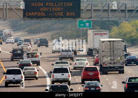 21 décembre 2005 ; Phoenix, AZ, États-Unis ; le trafic sur l'Interstate 10 dans le centre-ville de Phoenix, passe sous un panneau d'affichage électronique avertissant les automobilistes des niveaux élevés de pollution atmosphérique dans la région de Phoenix. Phoenix et sa banlieue luttent contre les niveaux élevés de pollution particulaire, le « nuage brun », chaque hiver. Le nuage brun est constitué de minuscules particules de dioxyde de carbone et d'azote gazeux. Ces substances sont déposées dans l'air principalement par la combustion de combustibles fossiles. Les voitures, les engins de construction, les centrales électriques, les tondeuses à gazon, les souffleurs de feuilles et plus contribuent au nuage, qui se forme lorsque la pollution est piégée Banque D'Images