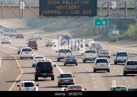 21 décembre 2005 ; Phoenix, AZ, États-Unis ; le trafic sur l'Interstate 10 dans le centre-ville de Phoenix, passe sous un panneau d'affichage électronique avertissant les automobilistes des niveaux élevés de pollution atmosphérique dans la région de Phoenix. Phoenix et sa banlieue luttent contre les niveaux élevés de pollution particulaire, le « nuage brun », chaque hiver. Le nuage brun est constitué de minuscules particules de dioxyde de carbone et d'azote gazeux. Ces substances sont déposées dans l'air principalement par la combustion de combustibles fossiles. Les voitures, les engins de construction, les centrales électriques, les tondeuses à gazon, les souffleurs de feuilles et plus contribuent au nuage, qui se forme lorsque la pollution est piégée Banque D'Images