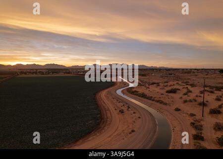 Vue aérienne des terres agricoles et du canal d'irrigation au lever du soleil près de Yuma, Arizona, montrant l'agriculture du désert et la lumière tôt le matin. Banque D'Images