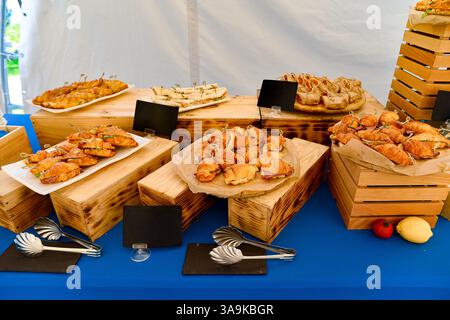 Superbement aménagé, le restaurant propose des croissants, des mini-sandwichs roulés et des amuse-gueules sur des caisses en bois et une nappe bleue. Banque D'Images