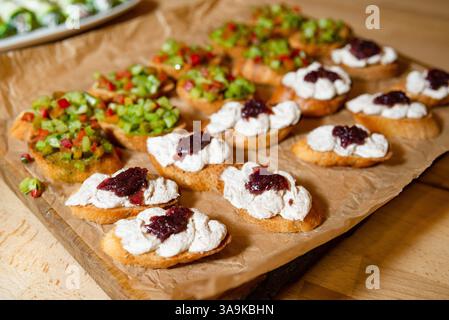 Gros plan d'une bruschetta croustillante garnie de pâte à tartiner crémeuse et de confiture, accompagnée d'une garniture de légumes coupée en dés sur du pain grillé. Banque D'Images