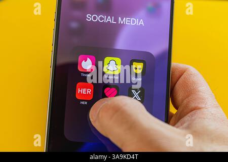 03.26.25 Lviv Ukraine Une main interagit avec un écran de smartphone affichant diverses icônes de médias sociaux. Des couleurs vives et un arrière-plan éclatant Banque D'Images