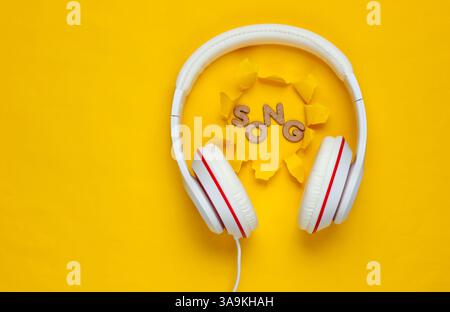Casque filaire blanc classique sur fond de papier jaune avec trou déchiré. Style rétro. 80s. Culture pop. Vue de dessus. Chanson de mot Banque D'Images