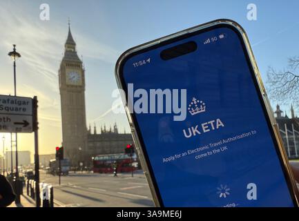Londres, Royaume-Uni. 31 mars 2025. Un téléphone portable avec l'application du gouvernement britannique pour demander un permis d'entrée ETA est conservé devant la tour Elizabeth. Toute personne voyageant au Royaume-Uni ces jours-ci devrait de toute urgence vérifier à nouveau sa boîte de réception. À partir de ce mercredi (2 avril), les voyageurs allemands qui n'ont pas de visa auront besoin du nouveau permis d'entrée électronique autorisation de voyage électronique (ETA). Crédit : Jan Mies/dpa/Alamy Live News Banque D'Images