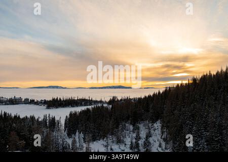 Coucher de soleil depuis le lac enneigé Štrbské au-dessus des nuages Banque D'Images